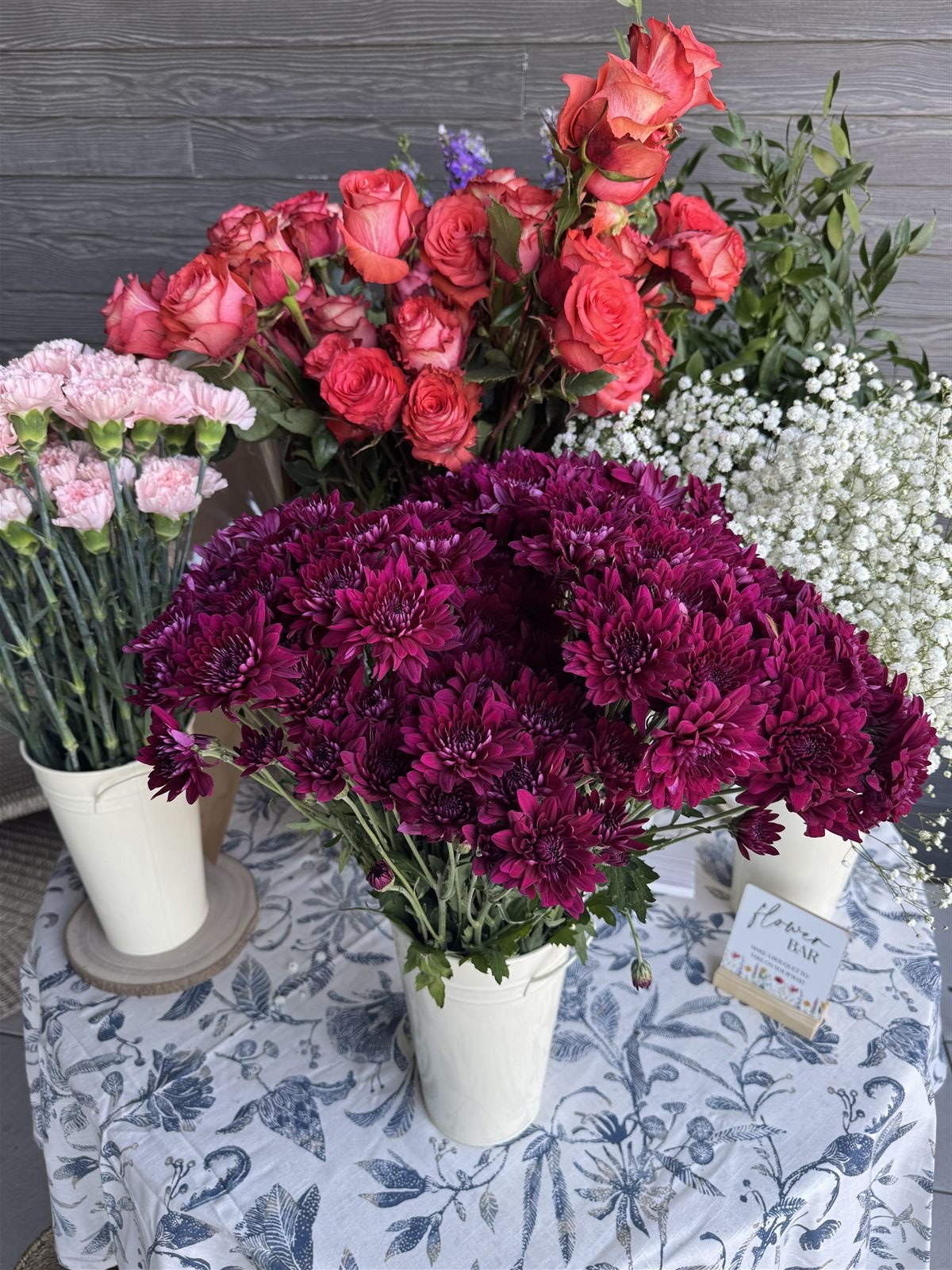 Flower bar table with buckets of roses, carnations, and a take-home bouquet sign