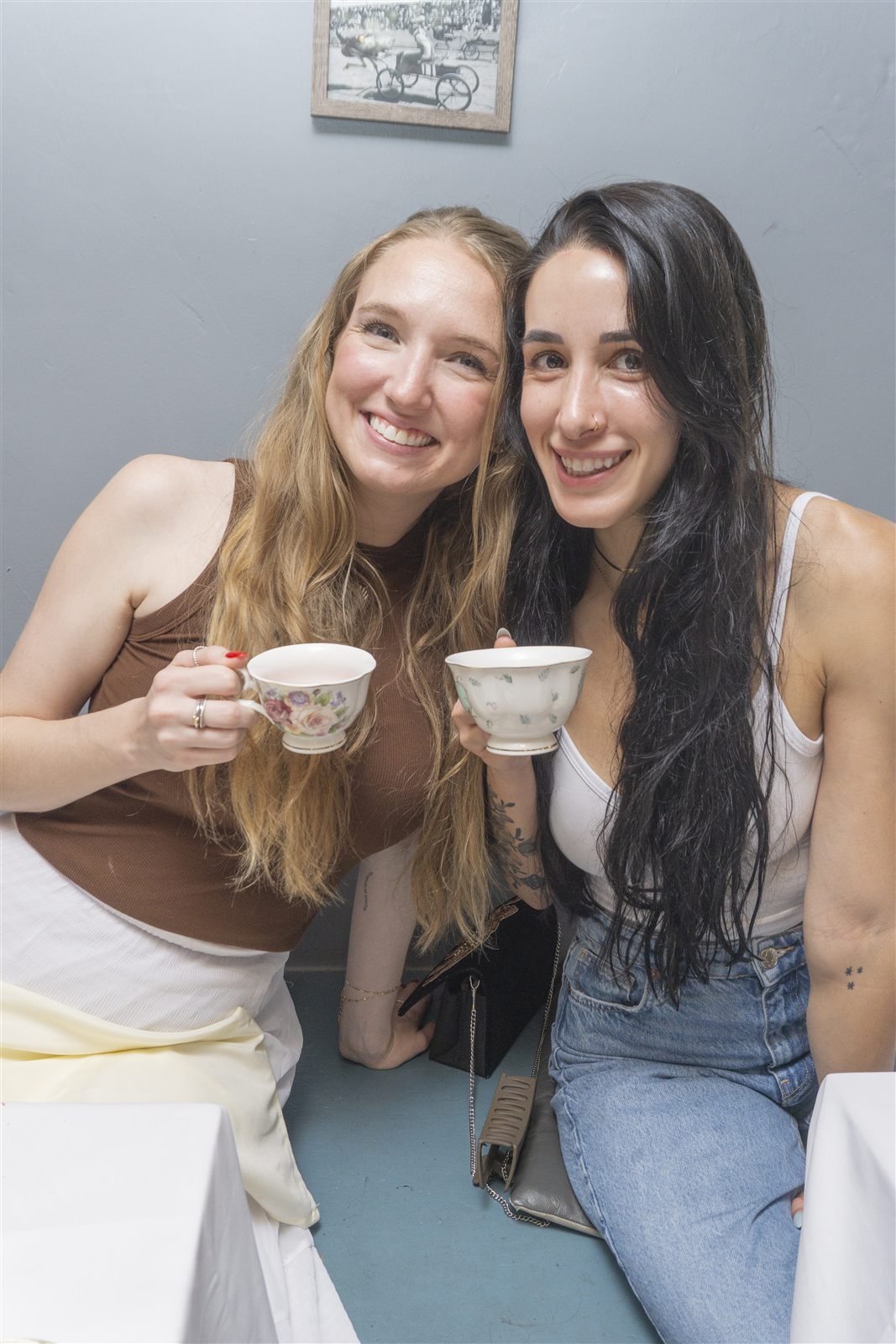 Two guests smiling and holding floral teacups at a hosted tea