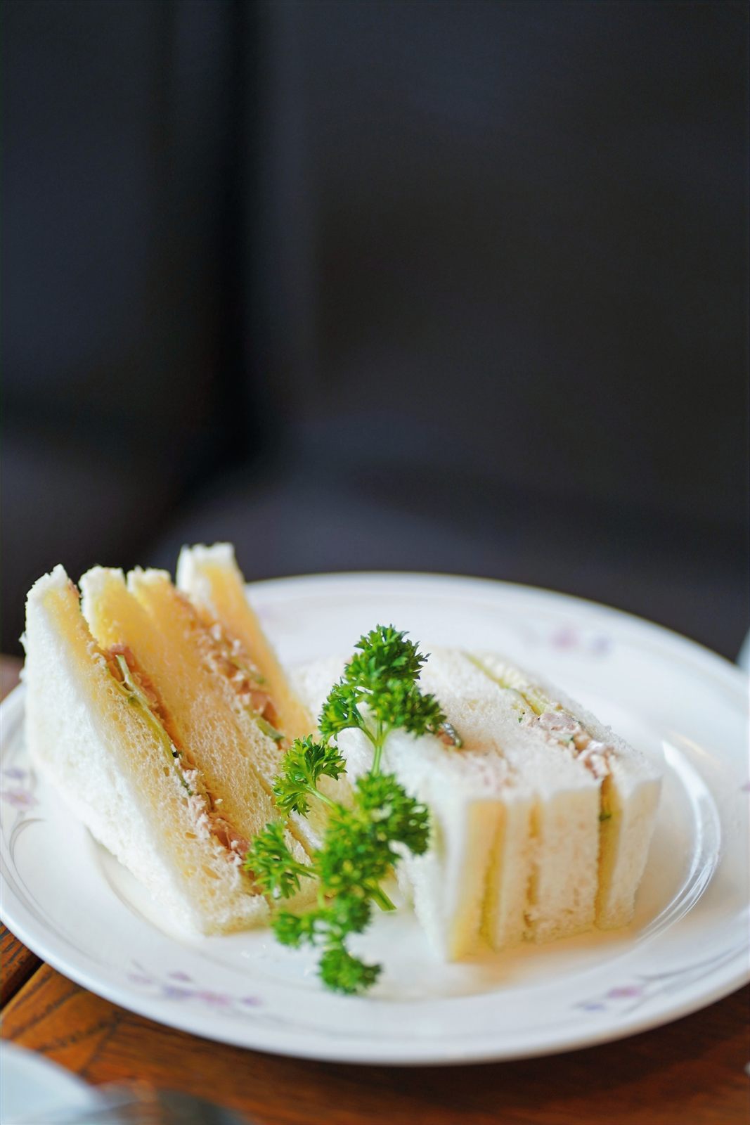 Crustless tea sandwiches on floral china with a parsley garnish